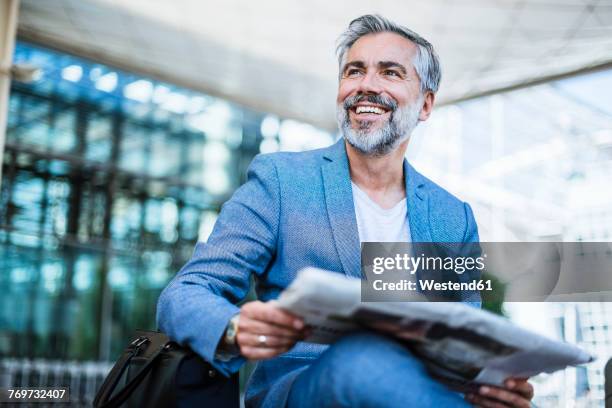 happy businessman reading newspaper - seitenblick stock-fotos und bilder