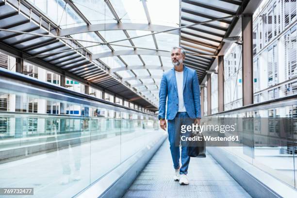 businessman walking on moving walkway - front on portrait older full body foto e immagini stock