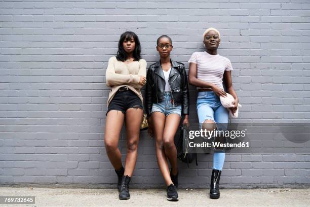 three friends leaning against grey wall - bored girlfriend stock pictures, royalty-free photos & images