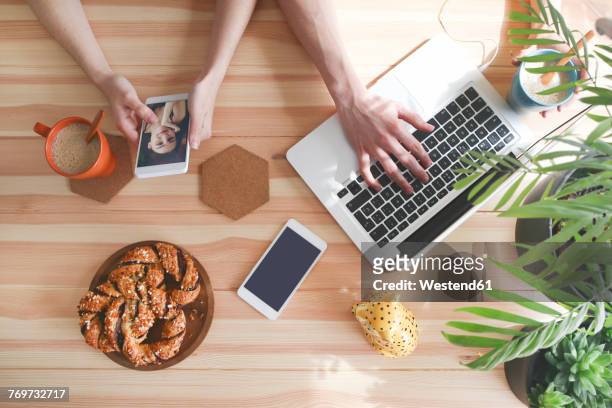 young couple having coffee and chocolate braids using laptop and smartphone, top view - convenience chocolate stock pictures, royalty-free photos & images
