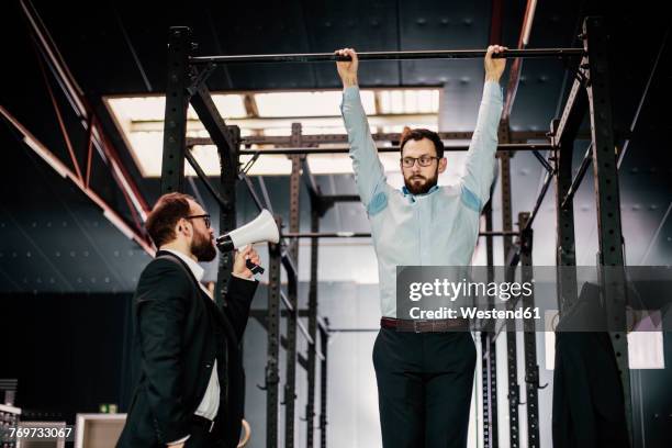 manager with megaphone giving businessman hanging on bar orders - horizontal bar stock pictures, royalty-free photos & images