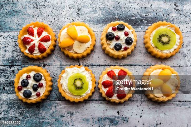 eight mini pies with whipped cream garnished with different fruits - banana cream cake stock pictures, royalty-free photos & images
