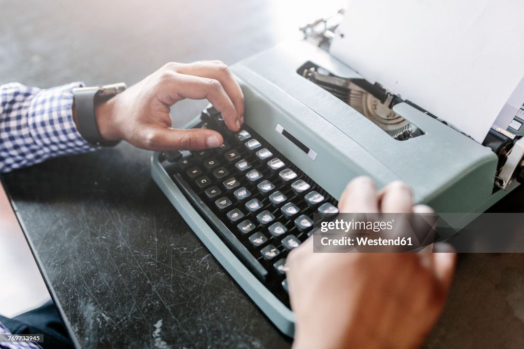 Close-up of man at desk using typewriter