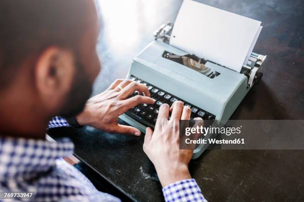 close-up of man at desk using typewriter - typewriter stockfoto's en -beelden