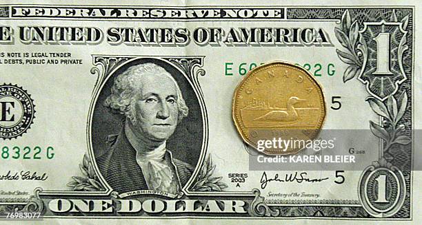 This 24 September, 2007 photo shows Canadian dollar and the US dollar. Canadians cheered 21 September, 2007 for their beloved loonie, reaching parity...