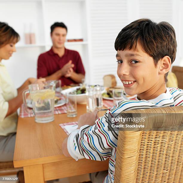 family including boy (12-13) sitting at table in kitchen - boy looking over shoulder stock pictures, royalty-free photos & images