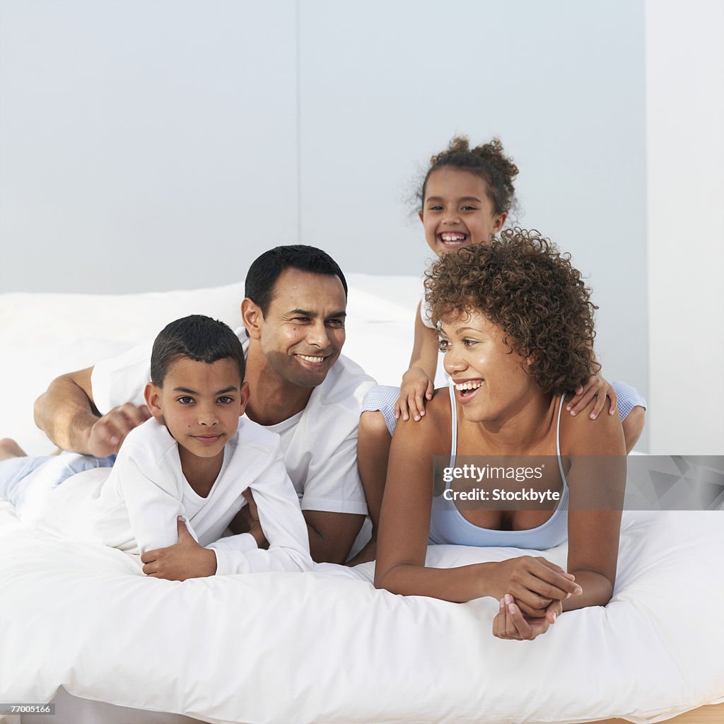 Parents with daughter (4-5 years) and son (6-7 years) lying on bed