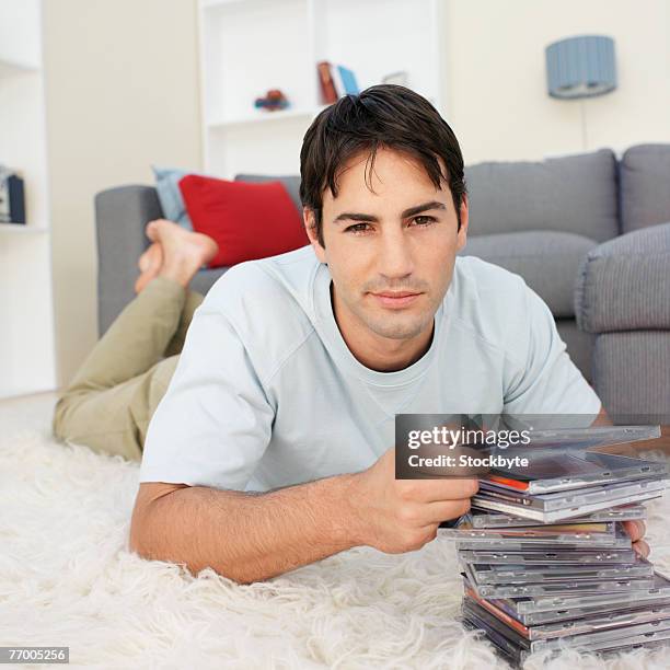 man looking at cd stack, lying on carpet, portrait - cd stack stock pictures, royalty-free photos & images