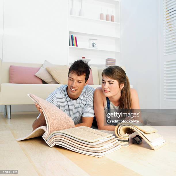 couple browsing through fabric samples on living room floor - carpet samples ストックフォトと画像