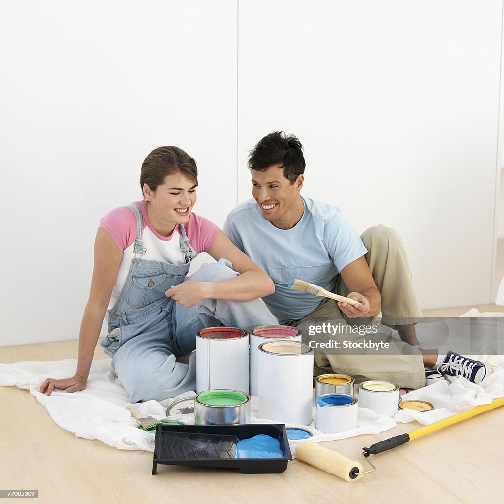 Couple sitting by paint pots in home