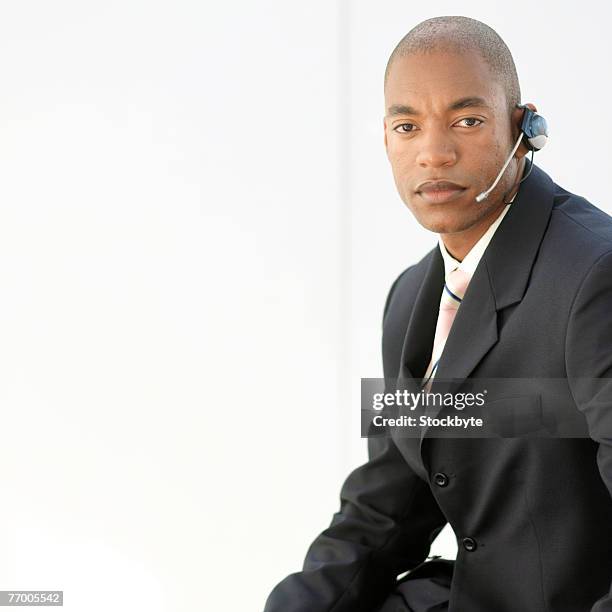 young businessman wearing hands free device, portrait, upper half - half shaved hair stockfoto's en -beelden