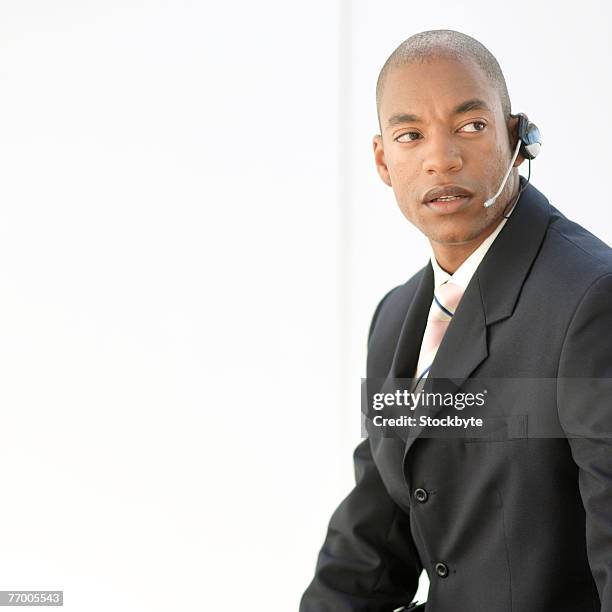 young businessman wearing hands free device, looking away, upper half - half shaved hair stockfoto's en -beelden