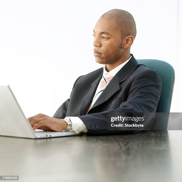 young businessman sitting at desk, using laptop, upper half - half shaved hair stockfoto's en -beelden