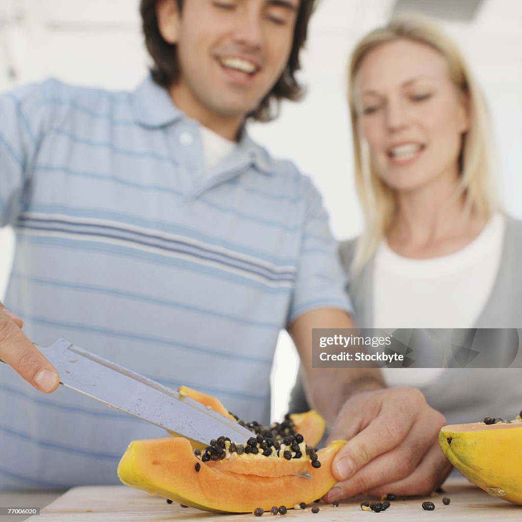 Couple slicing fruit in kitchen