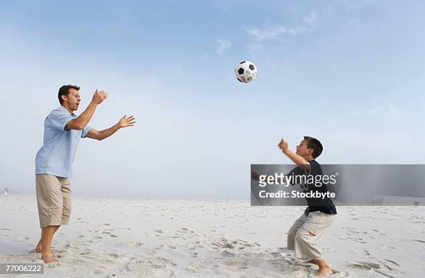 father and son (12-13 years) playing with ball on beach, side view - 12 13 years photos photos et images de collection