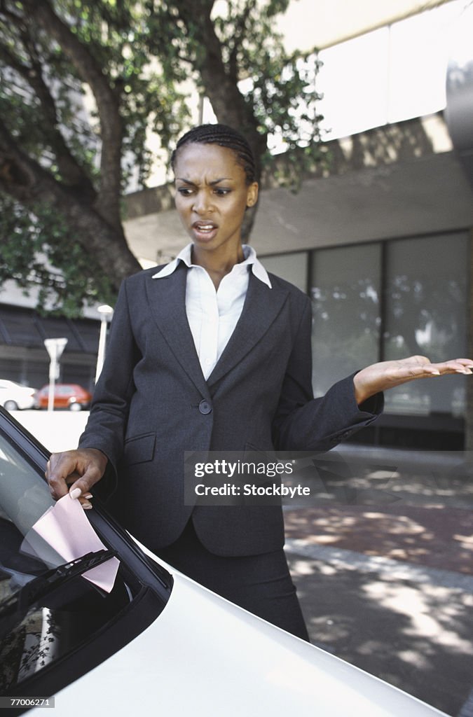 Business woman removing parking ticket from car