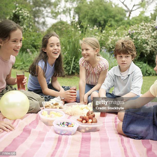 five children (8-11) having picnic in garden - somente crianças imagens e fotografias de stock