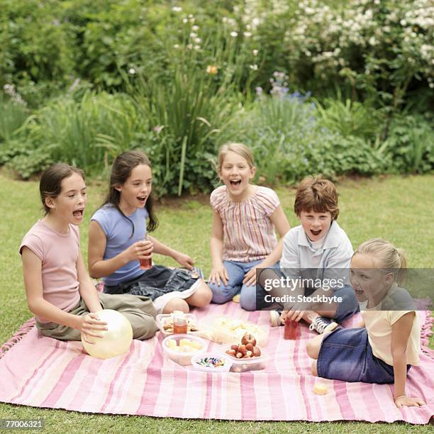 five children (8-11) having picnic in garden - somente crianças imagens e fotografias de stock