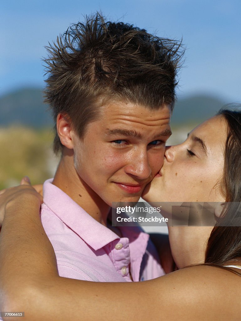 Teenage girl (16-17) kissing boy, close-up