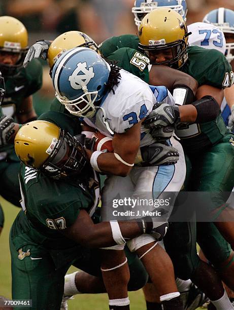 Running back Johnny White of the North Carolina Tar Heels looks for some yards as Defensive lineman Terrell McClain, Linebacker Donte Spires and...