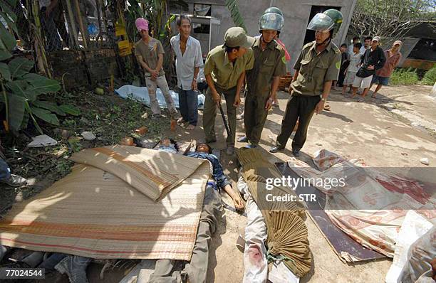 Policemen look at victims lying on the ground after the collapse of the Can Tho bridge under construction in Vietnam's southern province of Vinh...