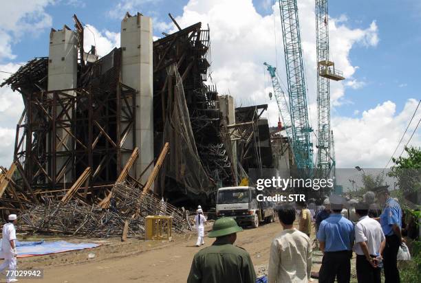 People stand watching at the site of the collapse of the Can Tho bridge under construction in Vietnam's southern province of Vinh Long on 26...