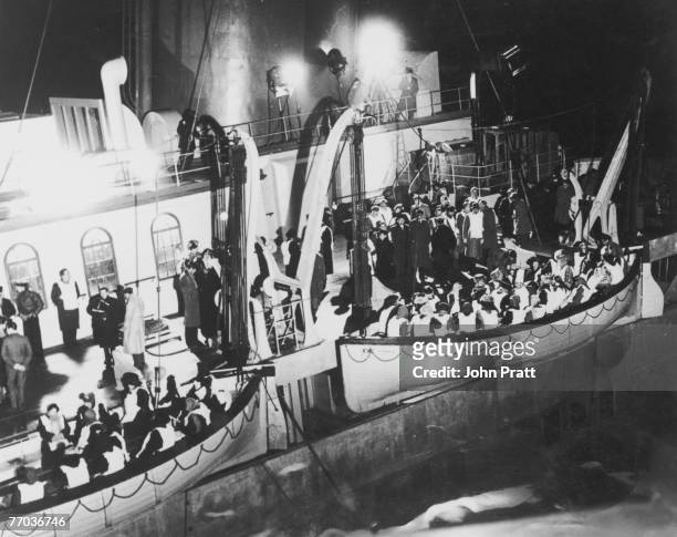 Overcrowded lifeboats are lowered from the stricken Titanic in a scene from Roy Ward Baker's 1958 film 'A Night To Remember', based on the sinking of...
