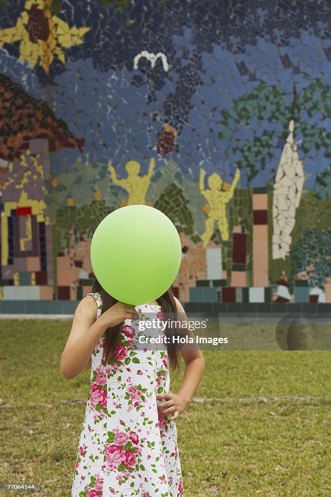 Girl covering her face with a balloon in a park