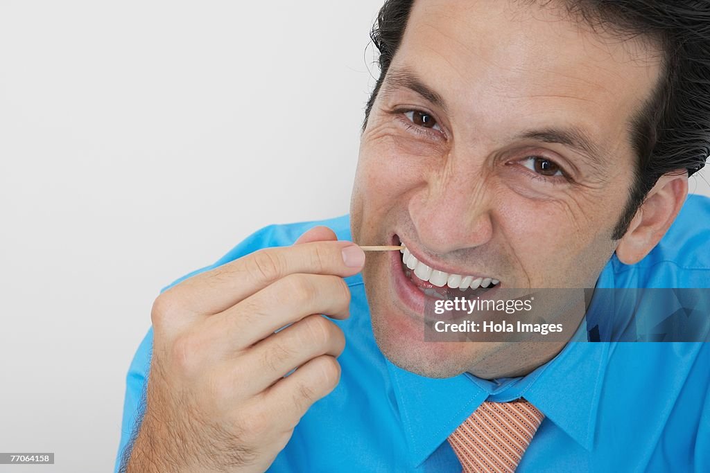 Portrait of a businessman picking his teeth in an office