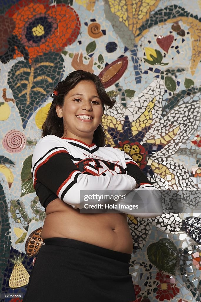 Portrait of a girl posing in front of a mosaic wall and smiling