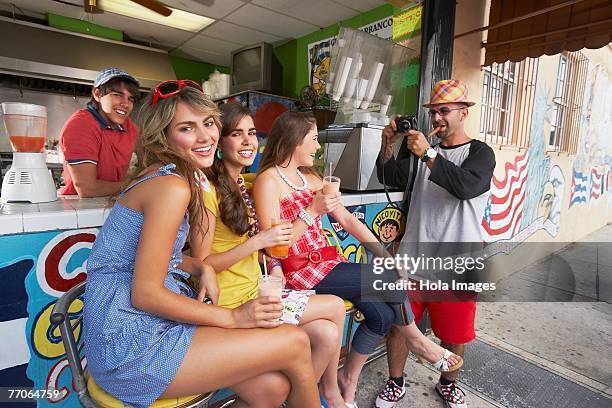 mid adult man taking a photograph of a teenage girl and her two friends - bar girl stock-fotos und bilder