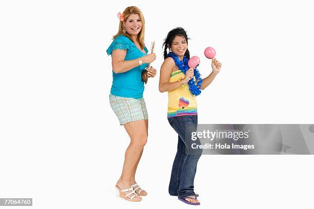 side profile of a young woman playing maracas and her mother playing ukulele - maraca stock pictures, royalty-free photos & images