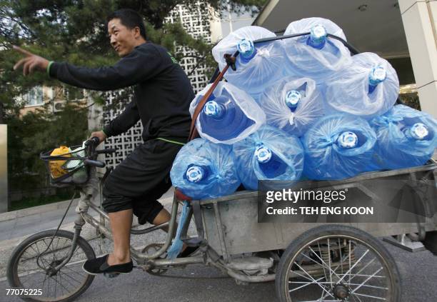 Chinese deliverer on a tricycle loaded with bottles drinking water in Beijing, 28 September 2007. China's capital Beijing plans to set up a special...