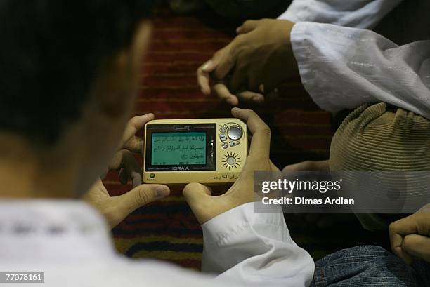Boys read a portion of text from The Koran displayed on a digital screen at a mosque on September 28, 2007 in Jakarta, Indonesia. Digital Koran is...