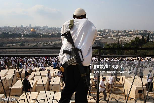 An armed religious Jewish settler watches the funeral of Rabbi Avraham Shapira September 28, 2007 in the ancient Jewish cemetery on the Mt. Of Olives...