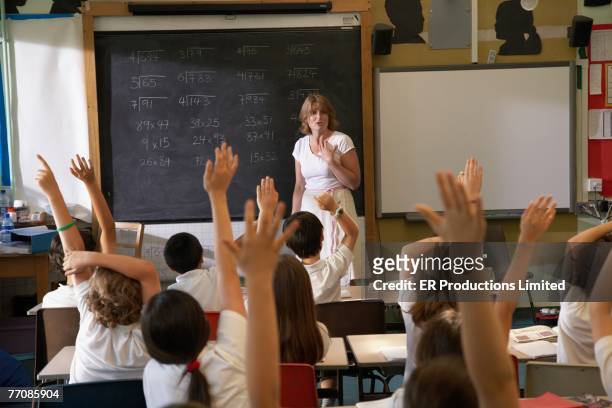 multi-ethnic children with hands raised in class - answering stock-fotos und bilder