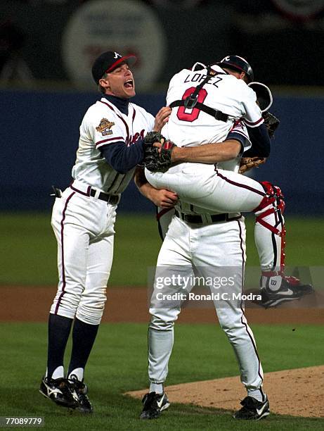 Atlanta Braves Javier Lopez jumps into the arms of Mark Wohlers as Chipper Jones joins in the celebration as the Braves win the World Series against...