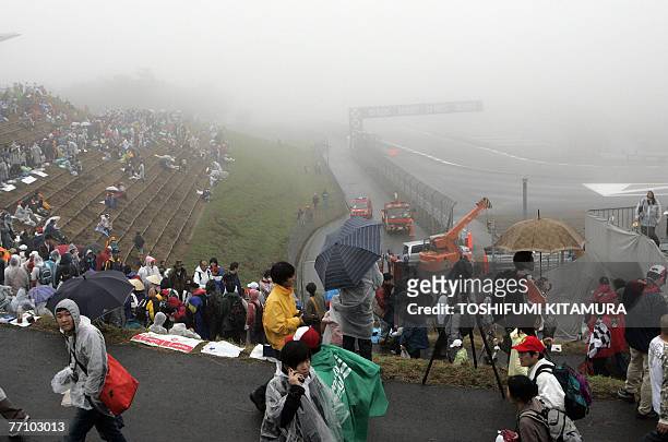 Visitors walk around the fog-covered track side after the practice session had been abandoned due to poor weather condition of the Japanese Formula...