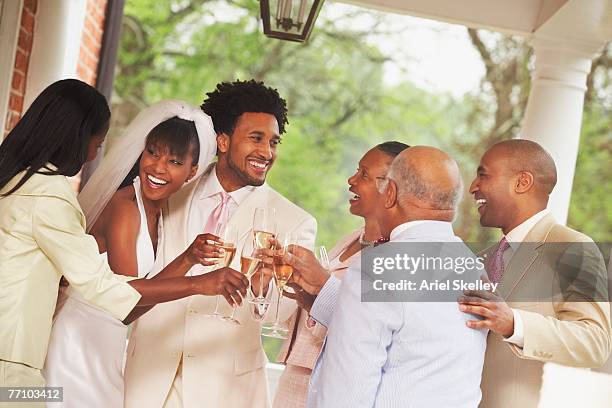 african american newlyweds toasting with family - african ethnicity wedding stock pictures, royalty-free photos & images