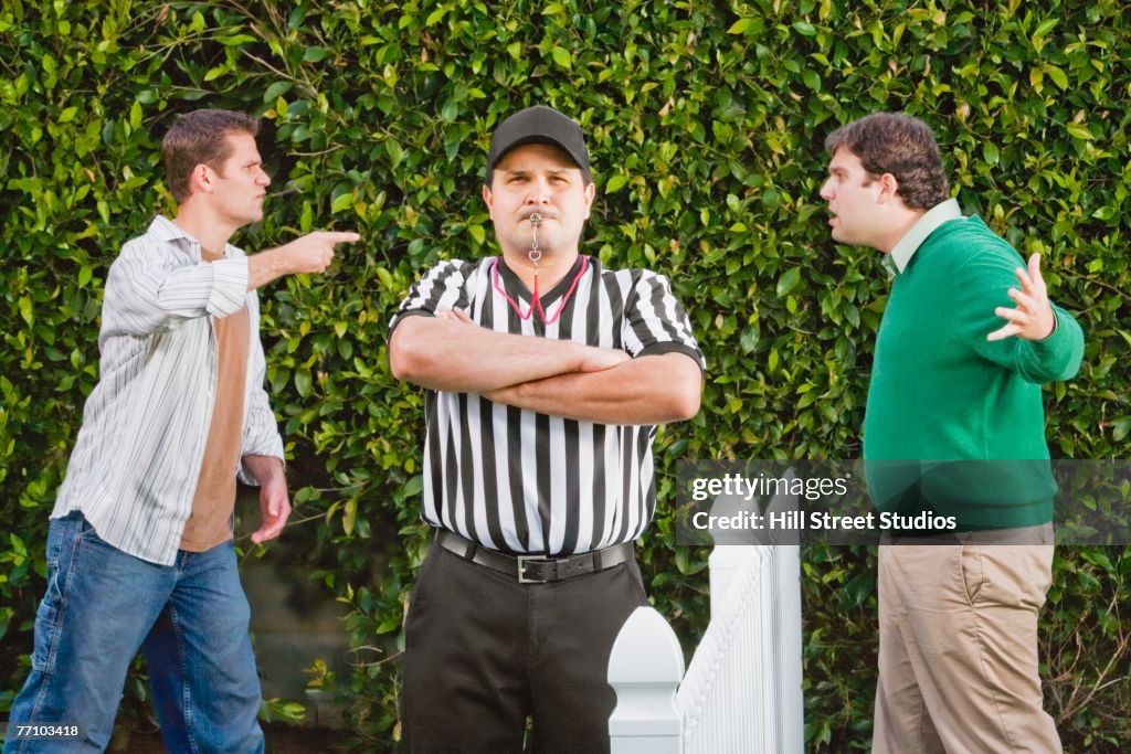 Hispanic referee between arguing neighbors