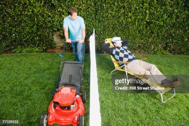 man mowing lawn while neighbor sleeps - jaloezie negatieve emotie stockfoto's en -beelden