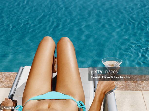 hispanic woman in lounge chair next to swimming pool - martini stockfoto's en -beelden
