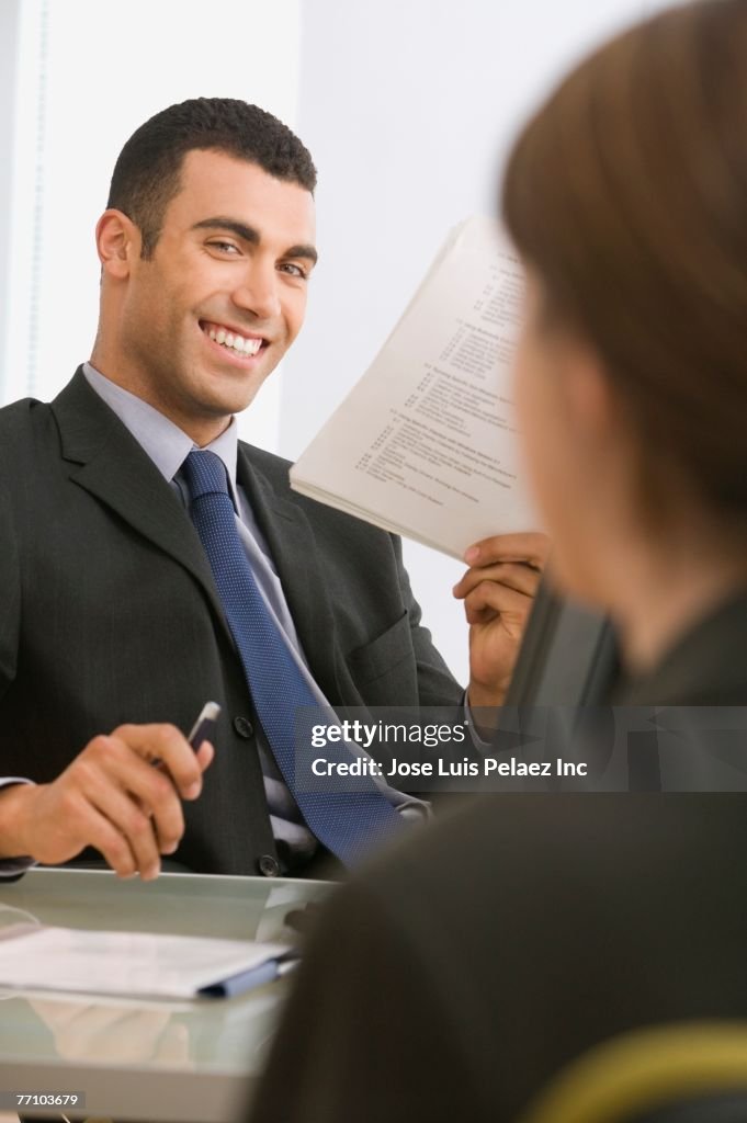 Hispanic businessman smiling at coworker
