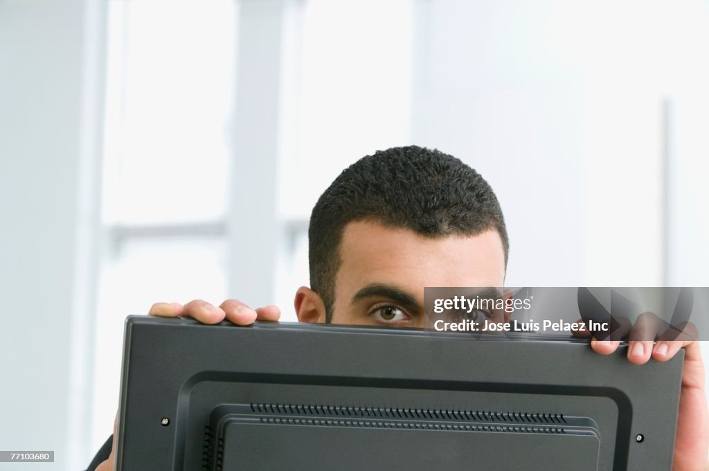 Hispanic businessman peeking over computer