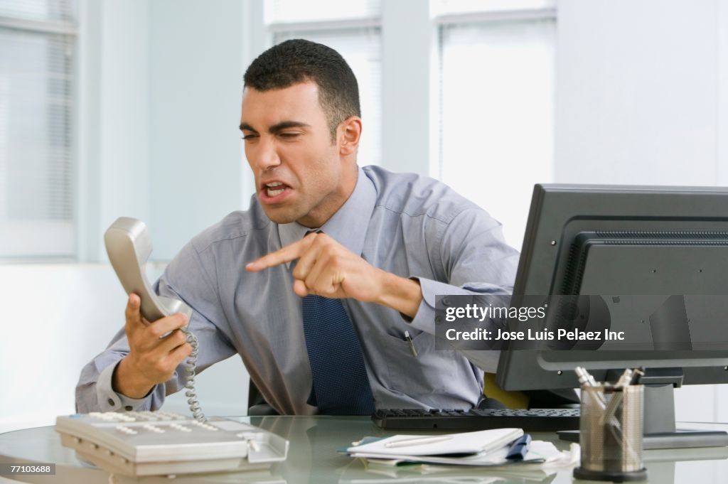 Hispanic businessman yelling at telephone