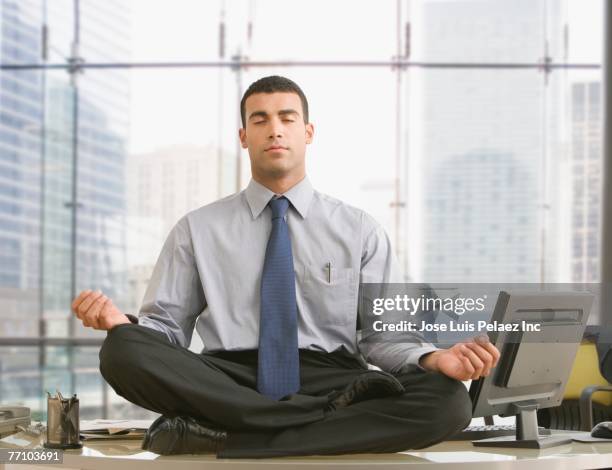 hispanic businessman meditating on desk - businessman meditating stock pictures, royalty-free photos & images