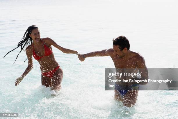 south american couple running in water - veralbern stock-fotos und bilder