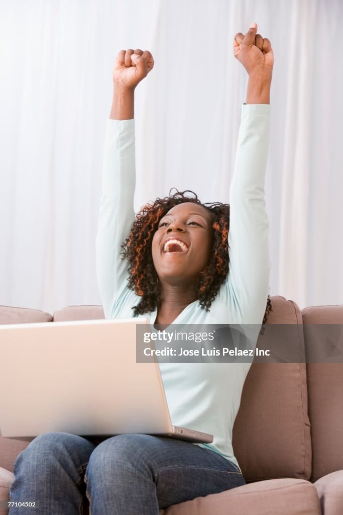 African American woman cheering on sofa