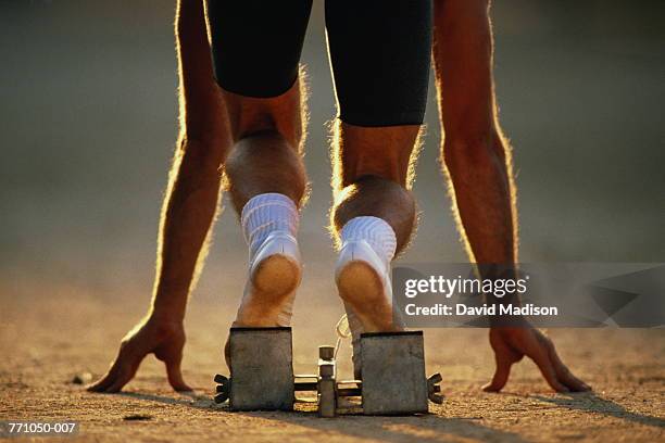 sprinter on starting blocks, low section, rear view - linha de largada imagens e fotografias de stock