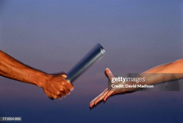relay team passing baton, close-up (blurred motion) - rivalry stock pictures, royalty-free photos & images